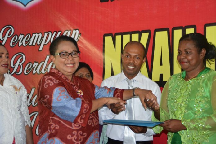 Menteri Pemberdayaan Perempuan dan Perlindungan Anak, Yohana Yembise, menyerahkan surat nikah pada salah satu pasangan nikah massal di aula Maranatha, KOta Sorong, Papua Barat, Kamis (21/12). (foto: ist/Penrem.)